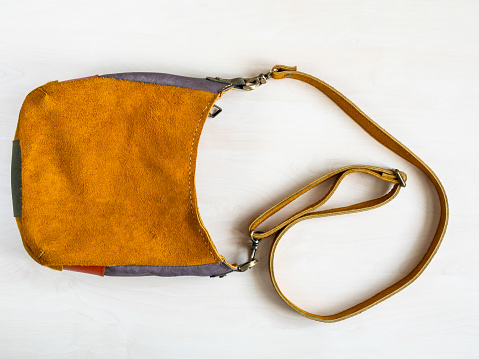 handcrafted cross body bag hand sewn from soft yellow suede on white background