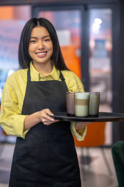 istock Woman holding tray of drinks looking at camera 1404239133