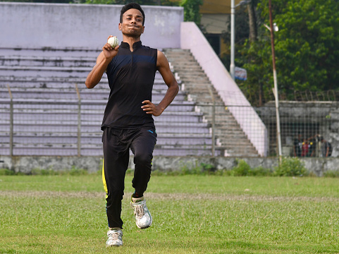 Rangpur, Bangladesh - Jun 19, 2022: Young cricketer running to bowl a cricket ball in a field