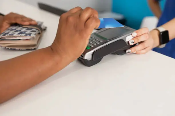 Photo of Black woman hand while paying through dataphone at the dental clinic