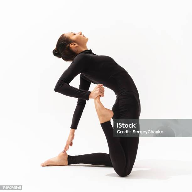 A Woman In Black Sportswear Practising Yoga Performs An Exercise Of Ushtrasana With Virasana A Camel And Hero Pose On A White Background Stock Photo - Download Image Now
