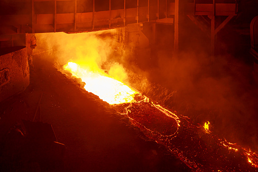 Hot melting pig iron in blast furnace workshop. Steel mill or iron foundry area.
