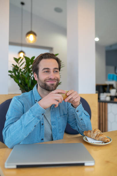 istock Happy man with cup sitting smiling to side 1404242944
