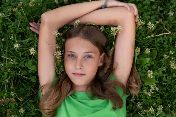 Young girl with green or blue eyes outdoors, looking strait forward to the camera. Shy look. Introspective. Not smiling