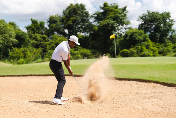 istock Asian man golfing on the course. He hits a golf ball on a sand field. 1404245608
