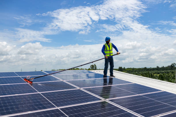 Worker Cleaning solar panels with brush and water. Worker cleaning solar modules in a Solar Energy Power Plan stock photo