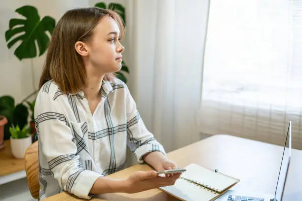 Photo of Young woman working on laptop at home. Cozy home office workplace, remote work, e-learning concept.