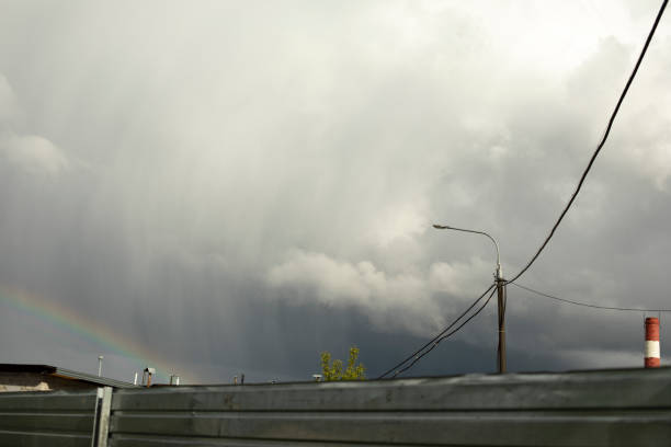 Rainbow in rainy sky. Celestial landscape in industrial area. Rain and blue clouds.