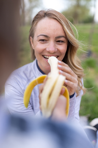 Close-up of happy mother and son sharing banana outdoors