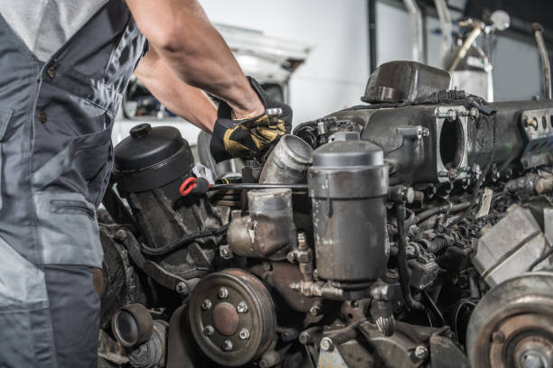 Mid adult mechanic carefully inspecting engine components in a professional workshop