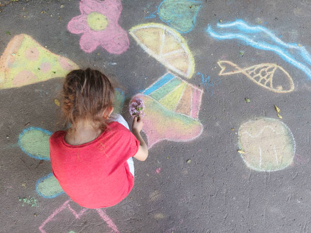 A child drawing in chalk on concrete asphalt. stock photo