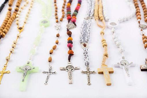 Person praying rosary. Catholic woman holding rosary in hand with candle lights bokeh background.