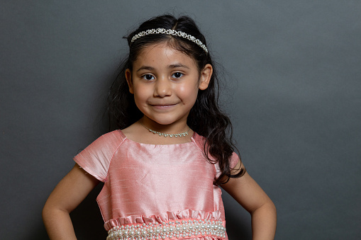 Studio shot of an adorable little girl standing and contemplating against a green background