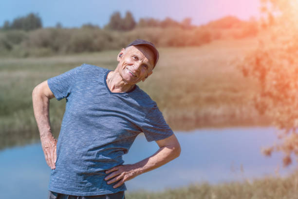 istock Older man wearing cap and headphones is exercising against river. 1404262264