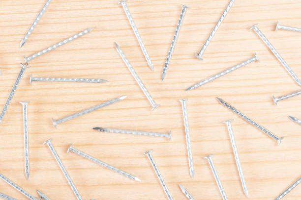 Scattering of metallic silver nails on wooden surface. Fasteners close up. DIY Assembling. Cloeup top view.