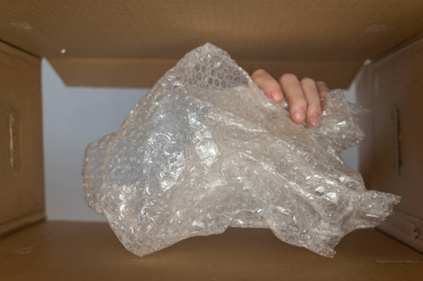 istock A man's hand puts bubble pack in a cardboard moving box. Plastic wrap or filler for postage. Bottom view. Inside view. Close-up. Selective focus. 1404263600