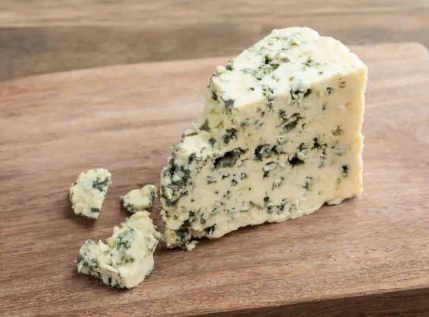 Gorgonzola cheese with pieces over wooden board.