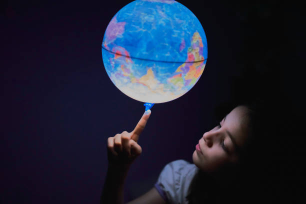 petite fille regardant dans l’obscurité un globe terrestre illuminé - elementary age focus on foreground indoors studio shot photos et images de collection