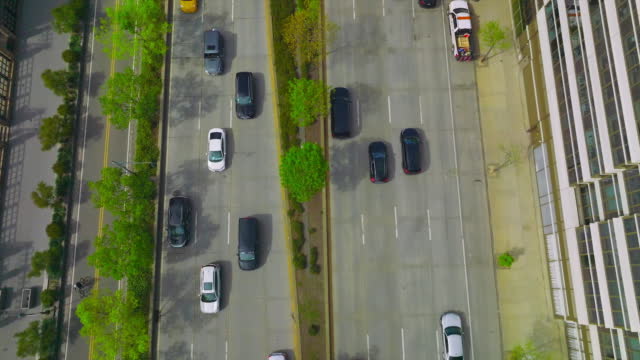 Wide road with several lanes with numerous cars driving on it. Drone footage along the busy motorway in New York.