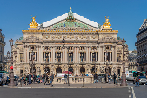 People walking in the Place de l´opera (Opera square) next to the Palais Garnier Opera House (Opera du Paris) at Paris city, France. Inaugurated in 1875, it is one of the most famous places in Paris.