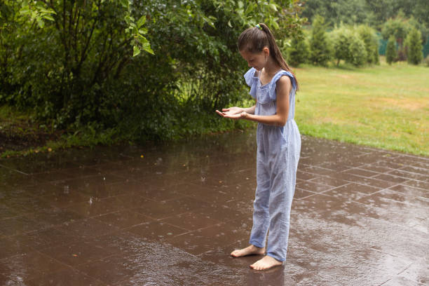 Girl in the rain and catches drops in the palm of her hand