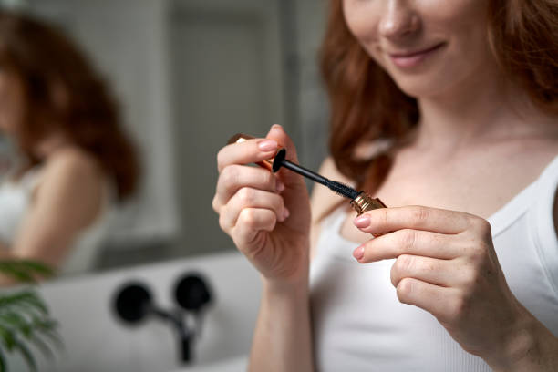 Close up of woman using mascara in the domestic bathroom stock photo
