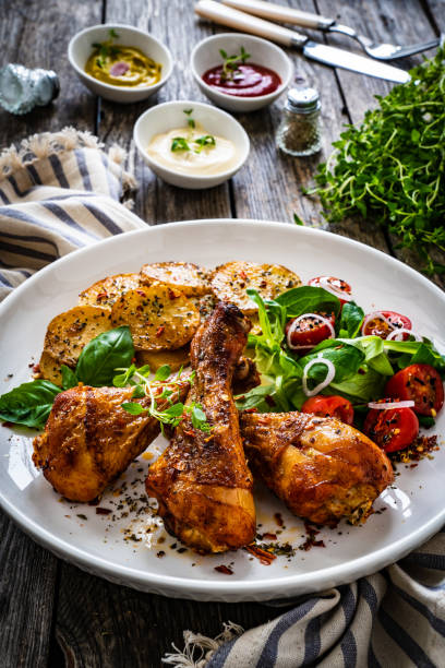 istock Barbecue chicken drumsticks with chips and greens on wooden table 1404279616