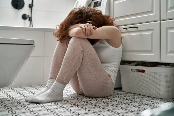 кавказская женщина с проблемами сидит на полу в ванной комнате - bulimia стоковые фото и изображения