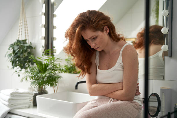 Caucasian woman with problems sitting in the bathroom stock photo