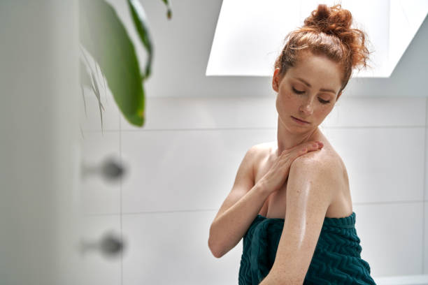 istock Young redhead caucasian woman using body balm after taking a bath 1404280232