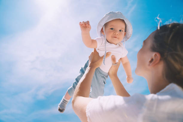 matka rzuca dziecko na błękitne niebo. szczęśliwa rodzina na świeżym powietrzu. mama i dziecko latem na łonie natury. pozytywne ludzkie emocje i uczucia. - baby beautiful caucasian one person zdjęcia i obrazy z banku zdjęć