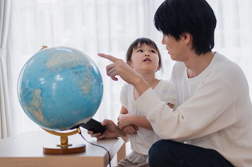 Family studying with dad using a globe