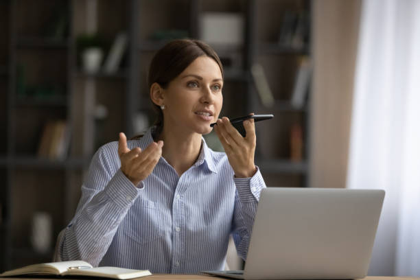 attractive woman sit at desk holding smartphone talk on speakerphone - 聽寫 個照片及圖片檔