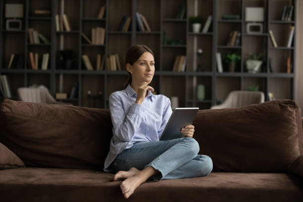 istock Pensive woman sit on sofa with digital tablet 1404289565