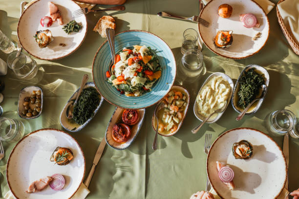 Couple Eating Lunch with Fresh Salad and Appetizers Closeup of multi generation family having Thanksgiving dinner. There are two mid adult couple and a mid 20's couple having a big feast, sharing food and love. Raki and meze Artichoke stock pictures, royalty-free photos & images