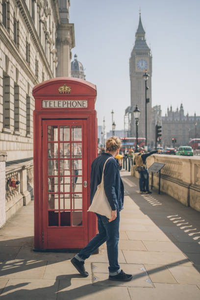 młody człowiek relaksuje się przed budką telefoniczną - london england england street light telephone zdjęcia i obrazy z banku zdjęć