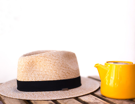 Yellow Teapot and Straw Hat on Cafe Table, Copy Space