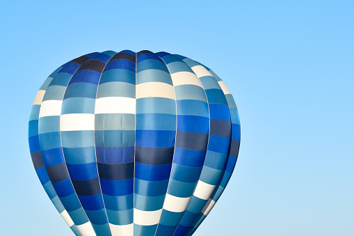 Picture of a blue hot air balloon against a clear sky.