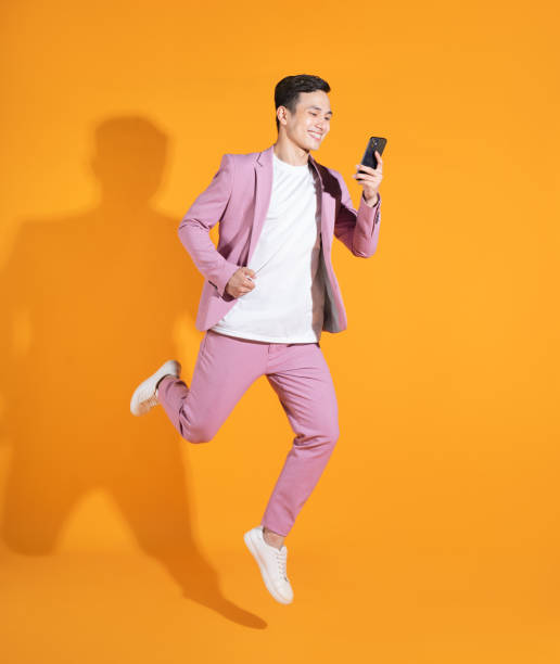 imagem completa de um jovem asiático em pé sobre fundo laranja - isolated cheerful businessman smiling - fotografias e filmes do acervo