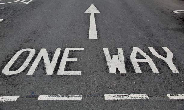 One Way Street Road Paint One way written with an arrow painted on the tarmac with white road paint at a car park near Edinburgh Scotland one way stock pictures, royalty-free photos & images