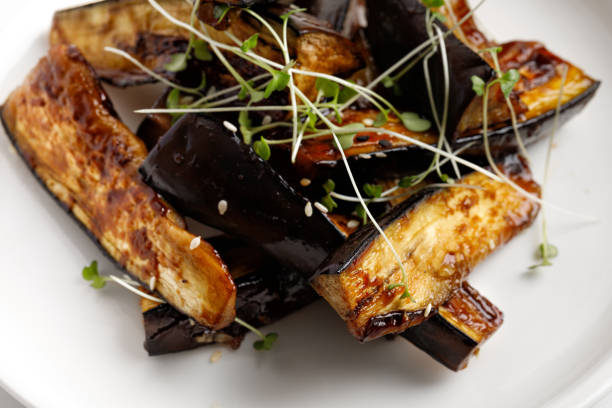istock Fried eggplant glazed with sauce, honey, microgreens on white plate and marble background, delicious vegan food. Close up. 1404333308