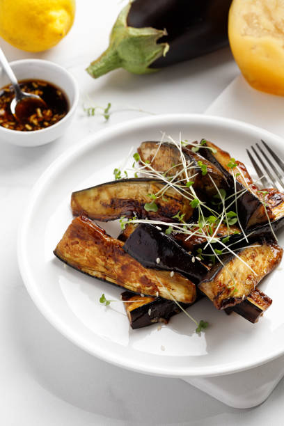 istock Grilled fried eggplant sticks with soy sauce and honey, garnished with microgreens, on white plate and white background, delicious vegetarian dish
