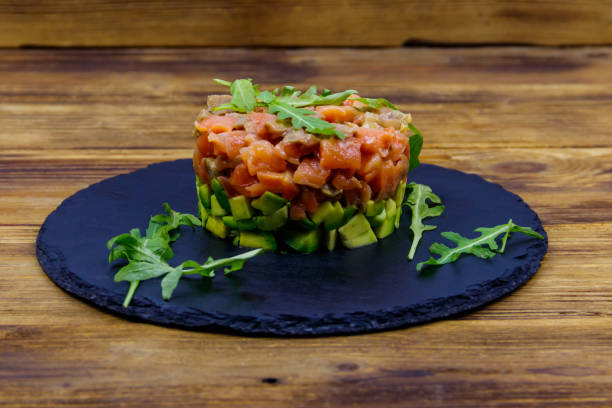 istock Salmon tartare with avocado and arugula on wooden table 1404333532