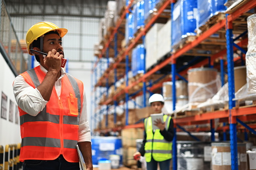 Warehouse or Supply chain engineer work with worker to check inventory at site line of High Rack Warehouse
