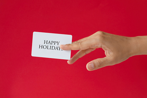 Close-up of a card in a woman's hand isolated on red.