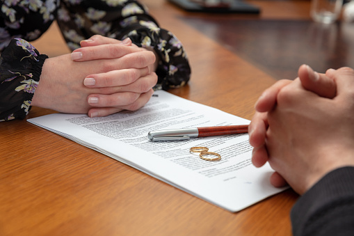 Firma de divorcio, documento de disolución matrimonial. Anillo de bodas y acuerdo sobre la mesa del despacho de abogados photo