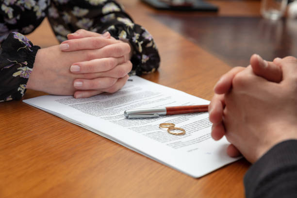 Divorce signature, marriage dissolution document. Wedding ring and agreement on lawyer office table stock photo