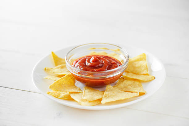Nachos, with tomato salsa, on white plate, selective focus.\