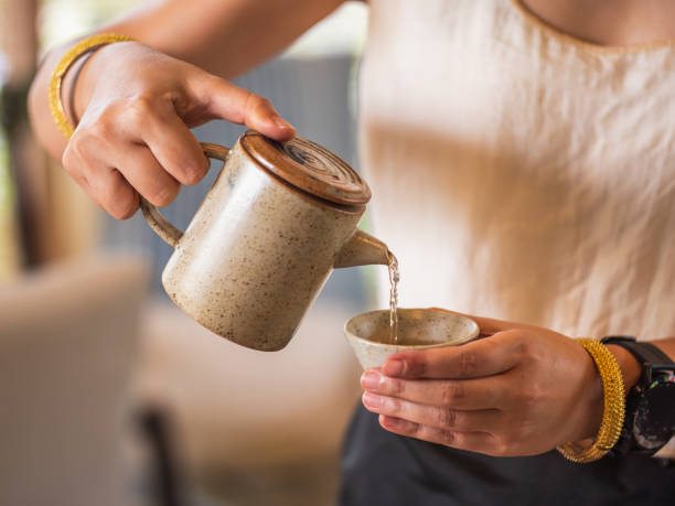 istock women pouring tea from teapot to tea cup. 1404338488