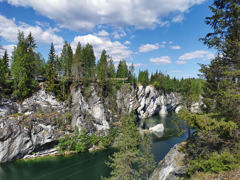 View of the picturesque rocky shores, the huge stone and the emerald water of the Marble Canyon in the Ruskeala Mountain Park on a sunny summer day.
